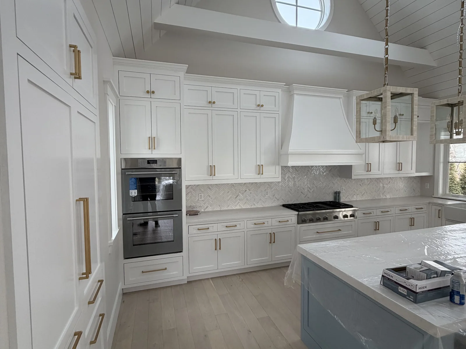 White kitchen remodel with island, double wall oven and vaulted ceiling