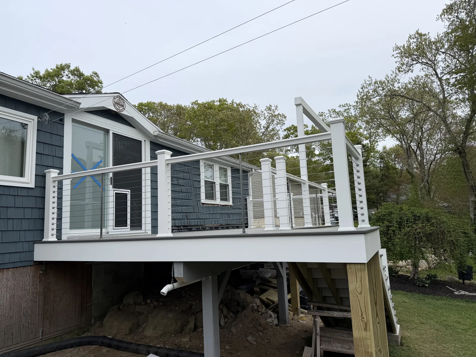Elevated deck with cable railing on a navy shingled home