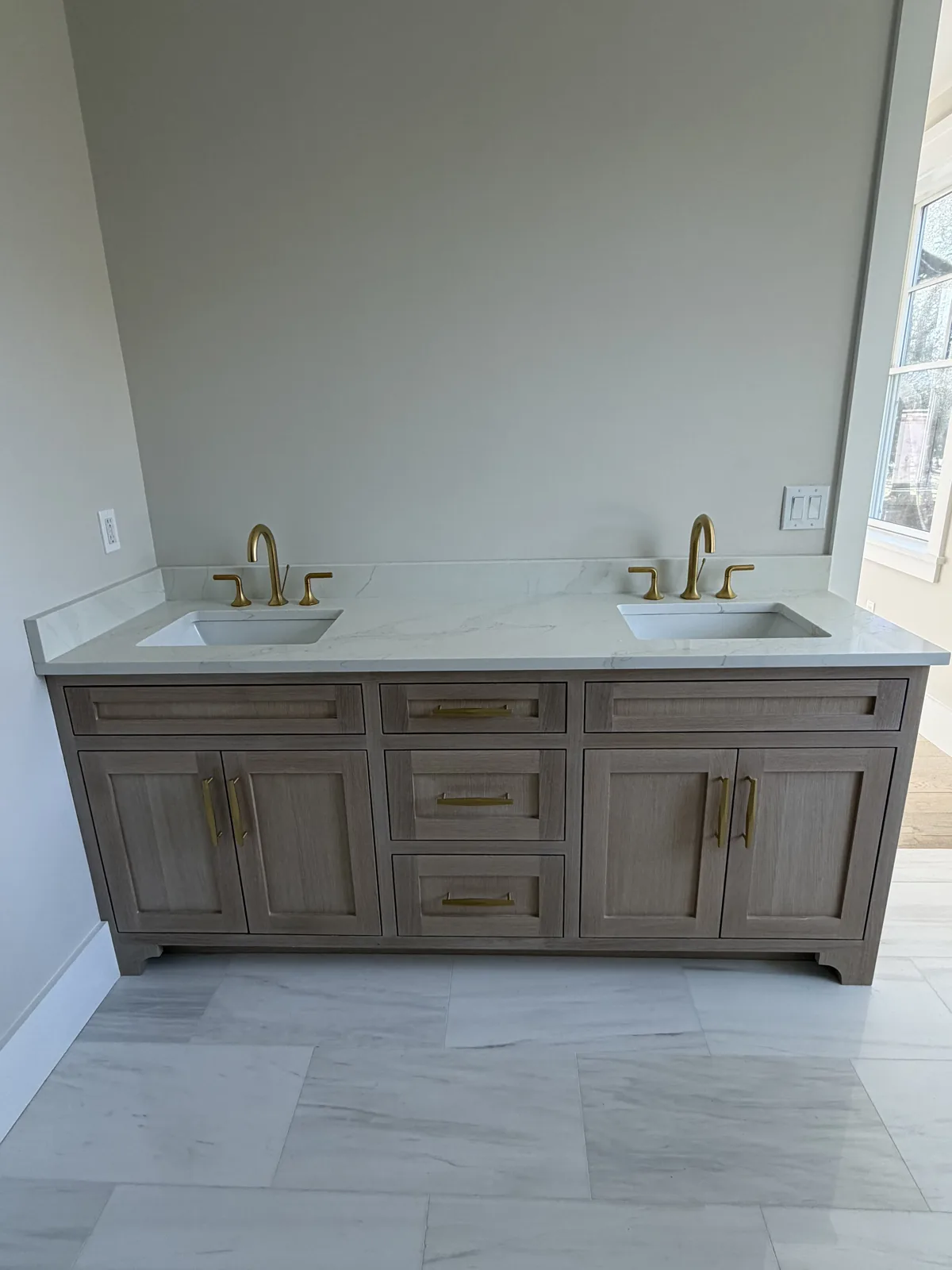 Double vanity with wood cabinetry, quartz top and brass faucets