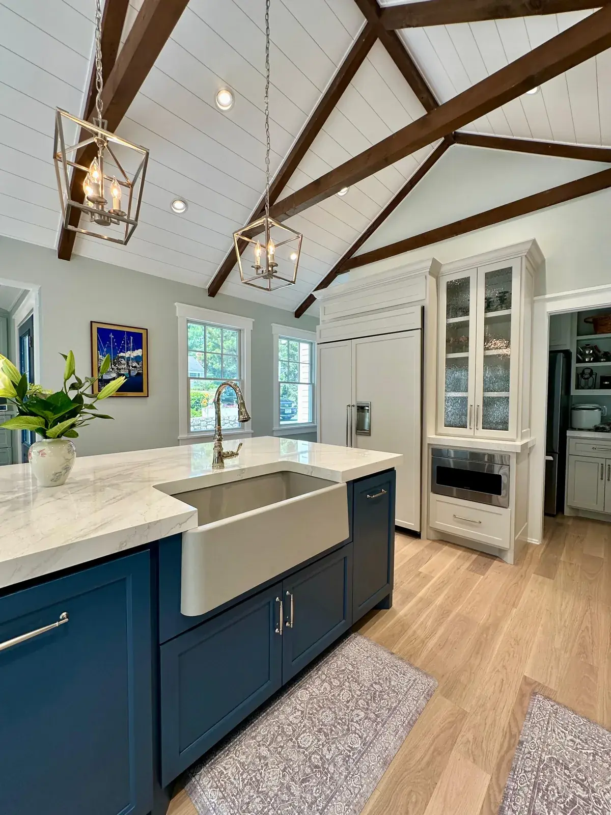 Kitchen with exposed ceiling beams, navy island and farmhouse sink