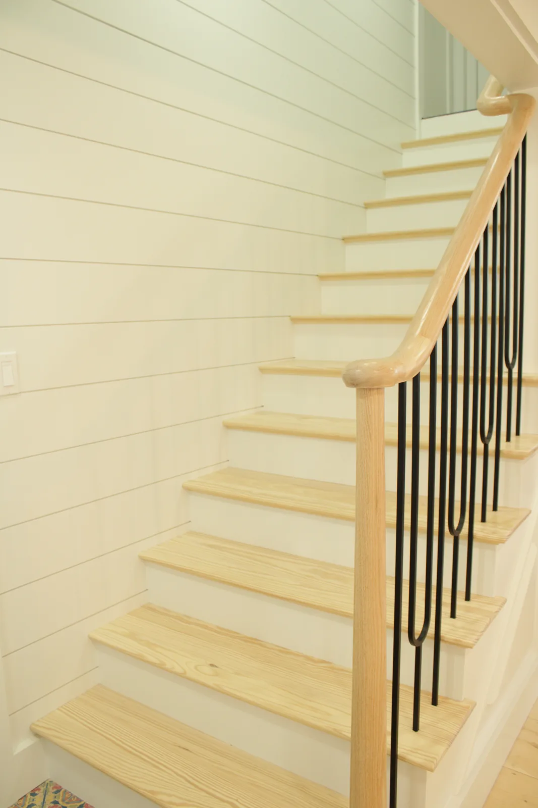 Custom staircase with wood treads, black balusters and shiplap wall