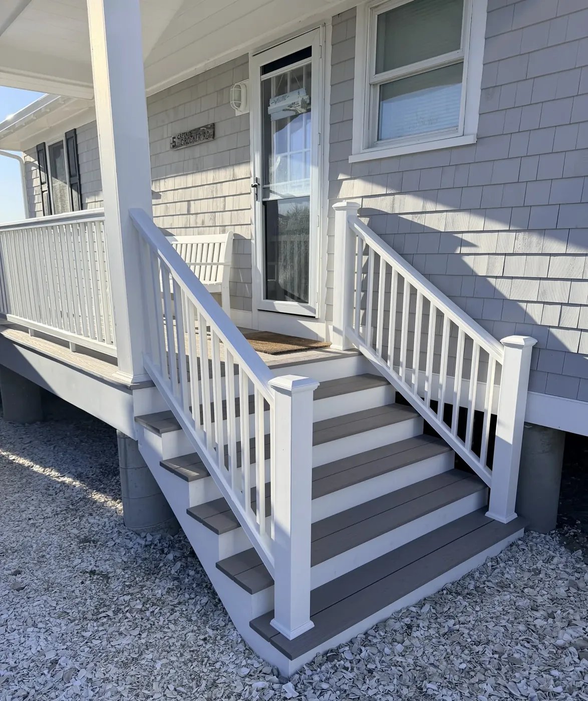 Exterior entry stairs with white railings against shingle siding