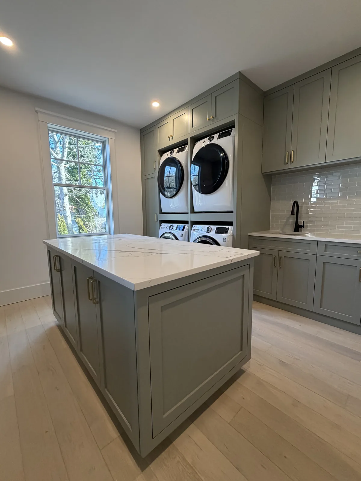 Laundry room with island, cabinetry and stacked washer and dryer