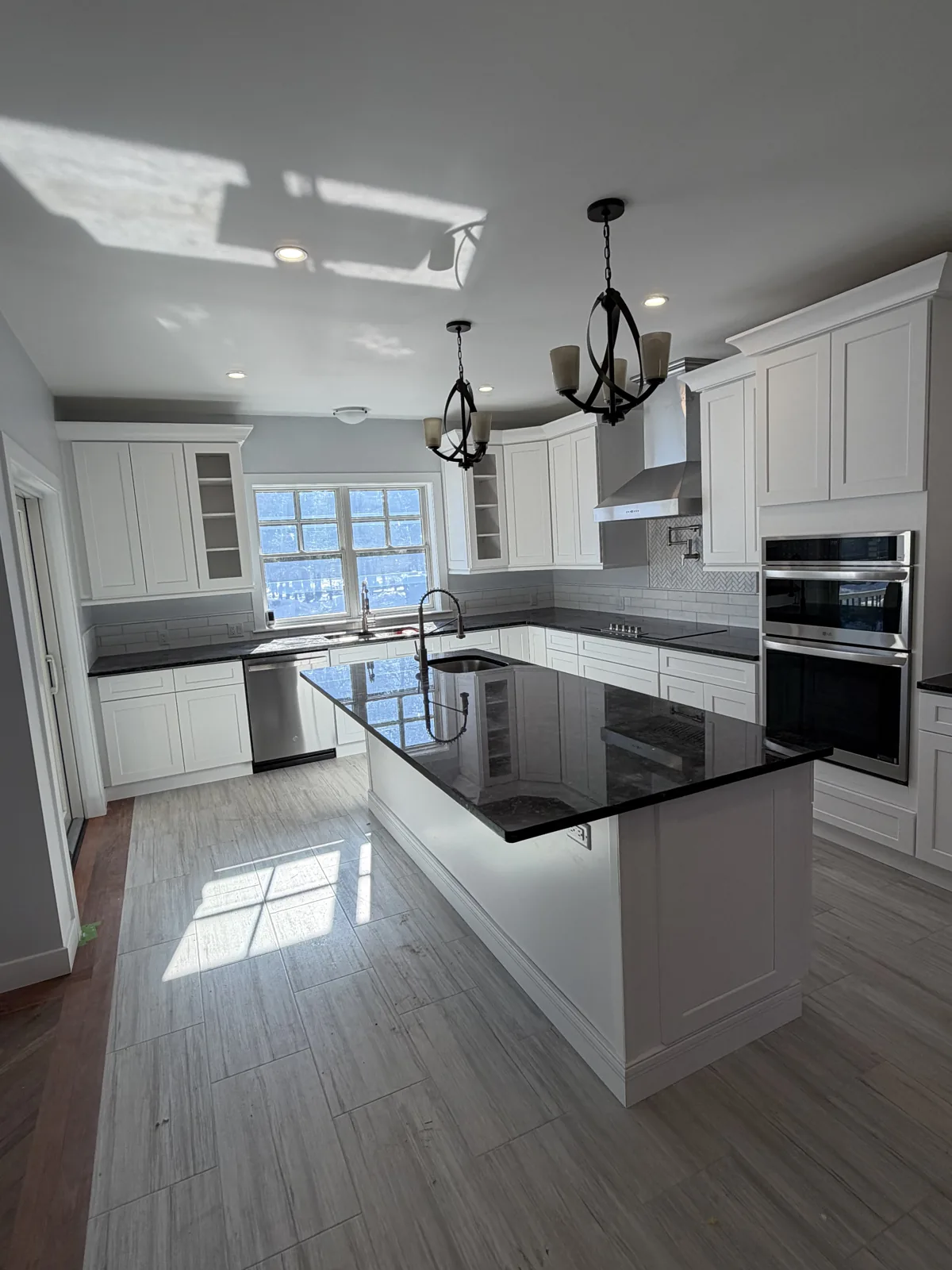 Modern kitchen with black island, chandelier and glossy floors