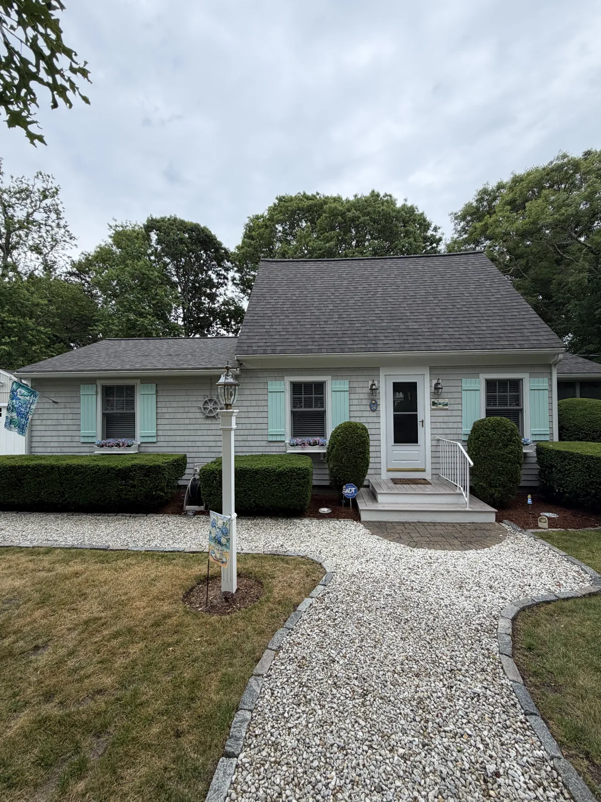 Light green Cape home with stone walkway and new trim