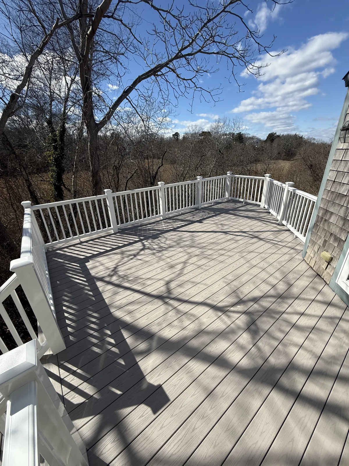 Large deck with white railing overlooking open land