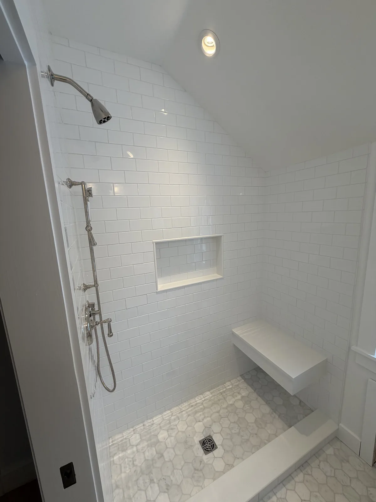 Walk-in shower with white subway tile, bench and storage niche