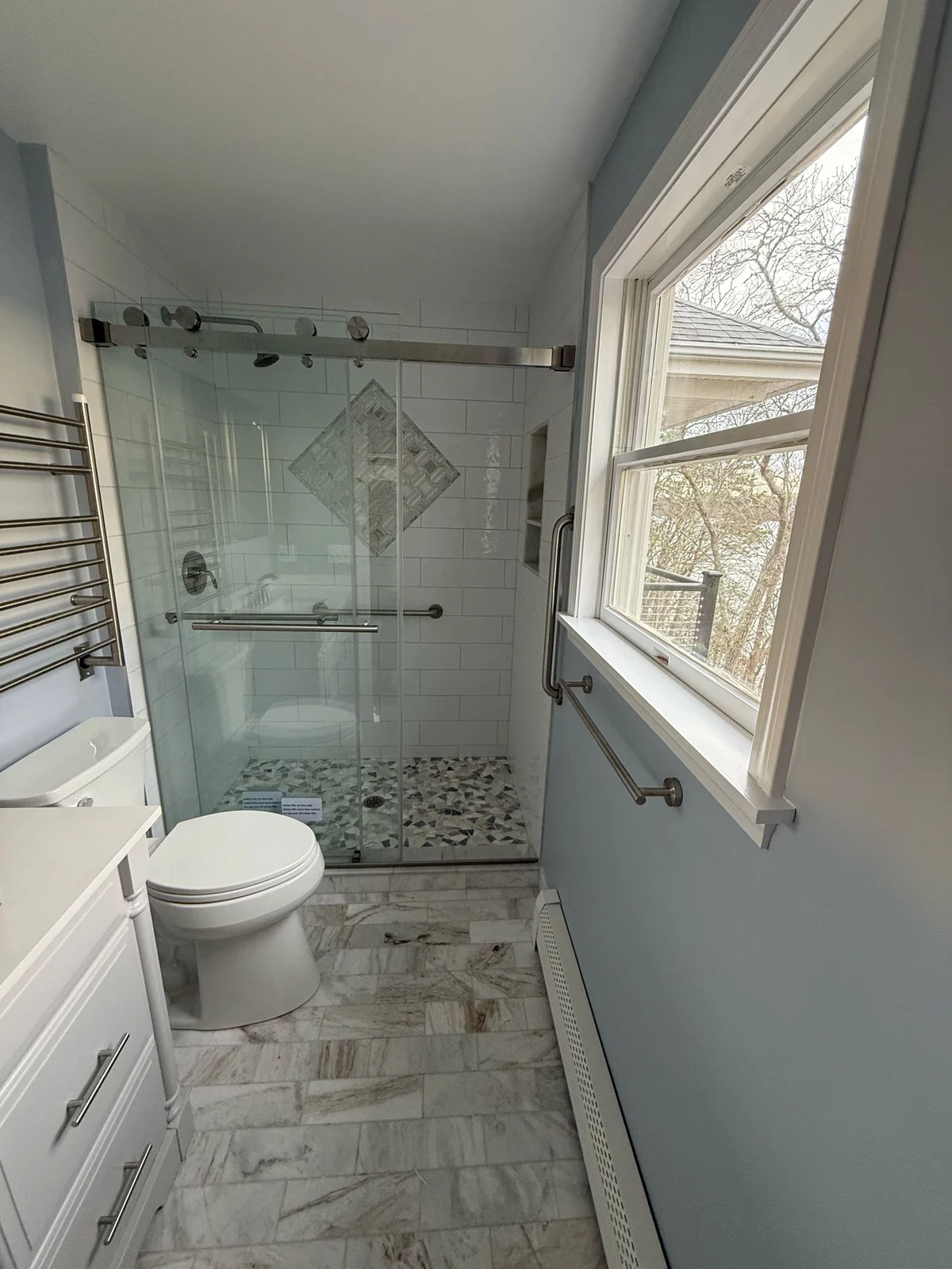 Glass shower enclosure in a narrow bath
