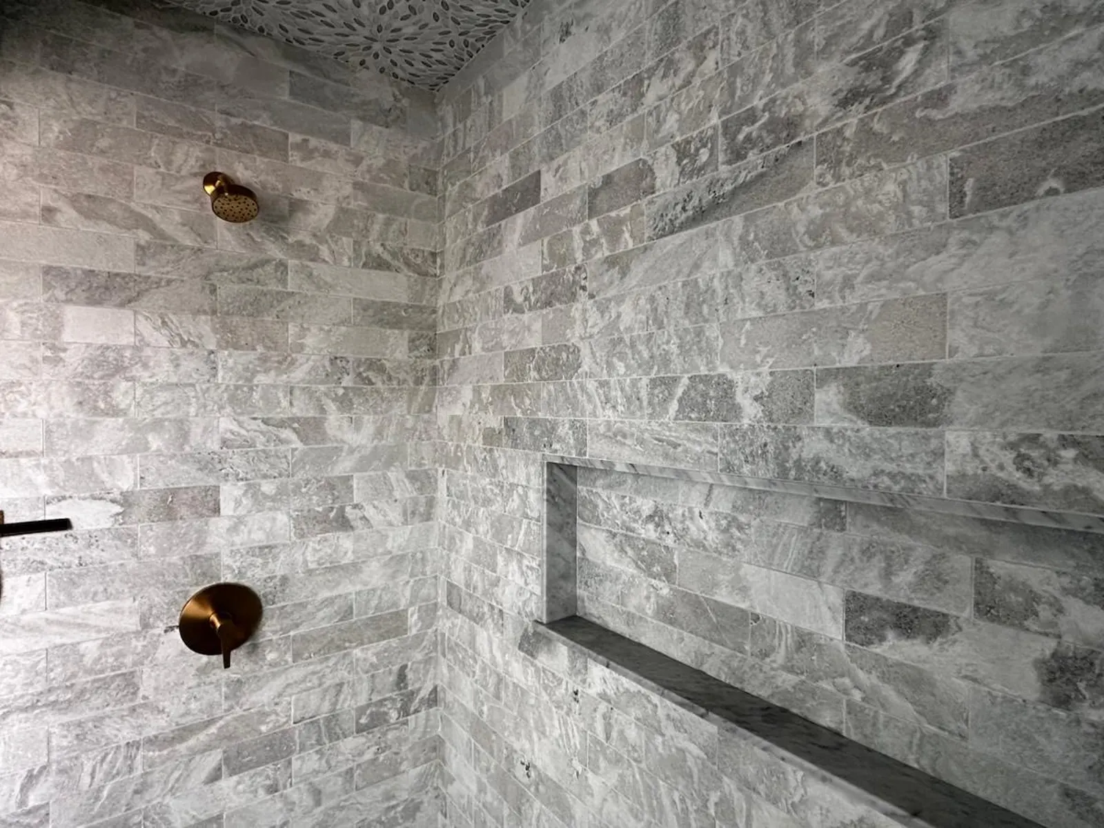 Stone tile shower with a full-width niche