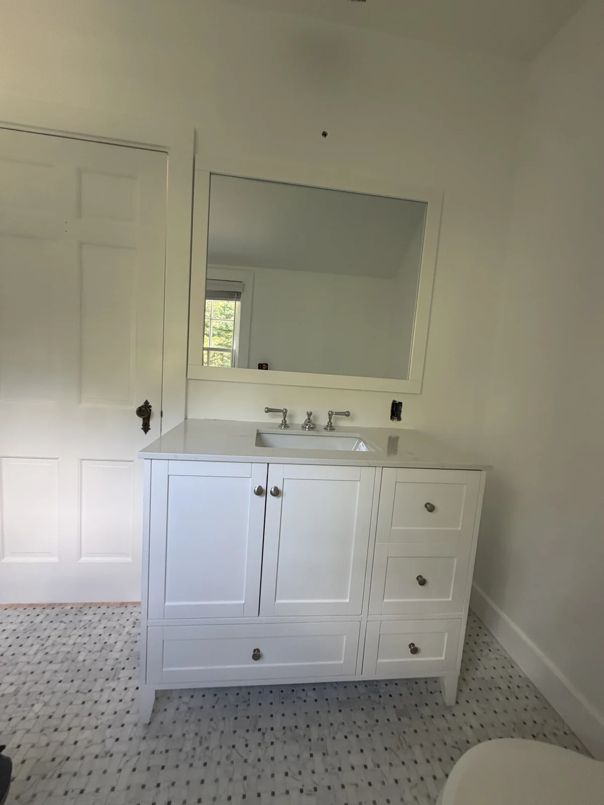 White shaker vanity with a quartz top and a marble basketweave tile floor