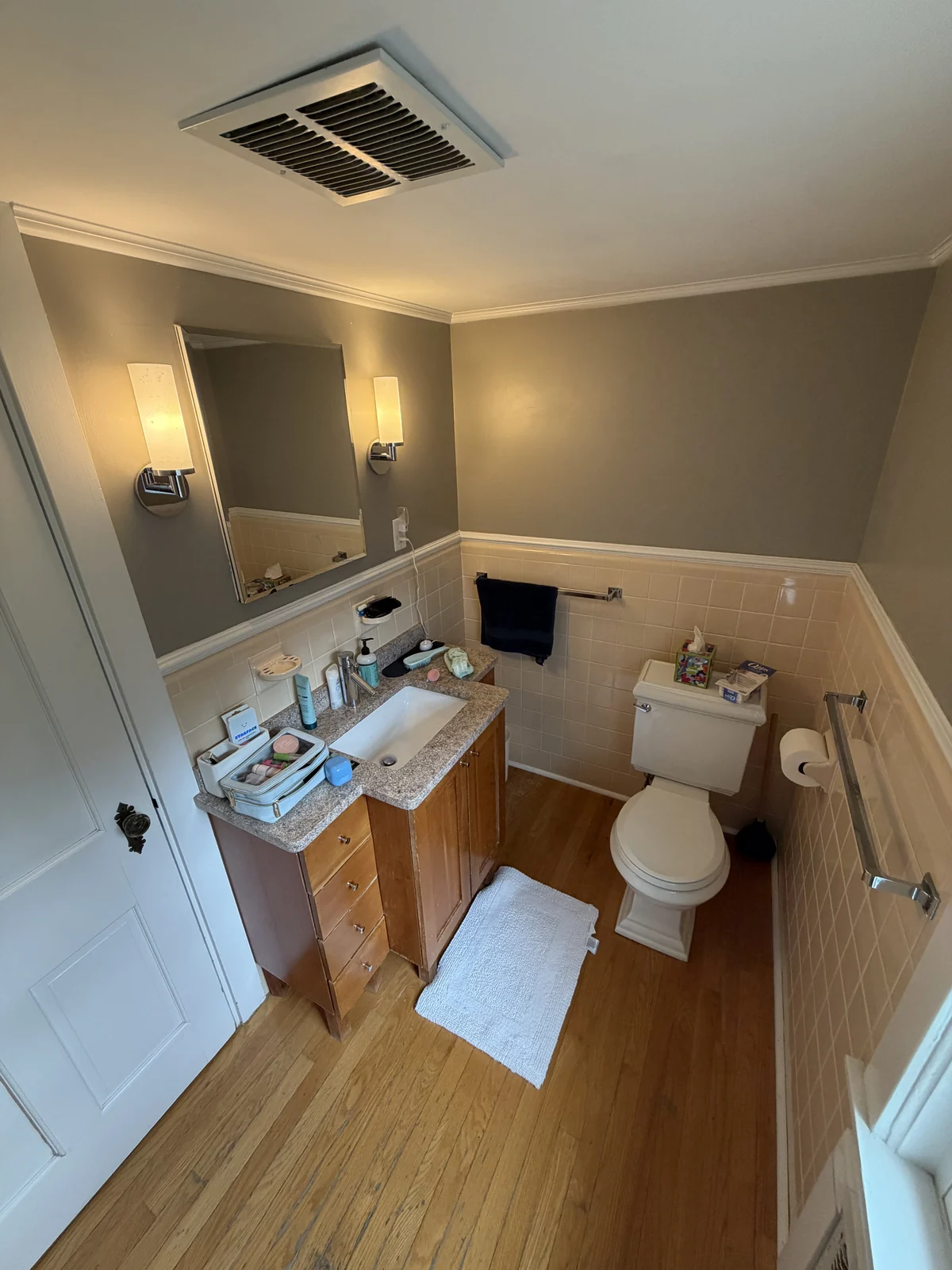 Bathroom before the remodel with a wood vanity, beige wall tile and a hardwood floor