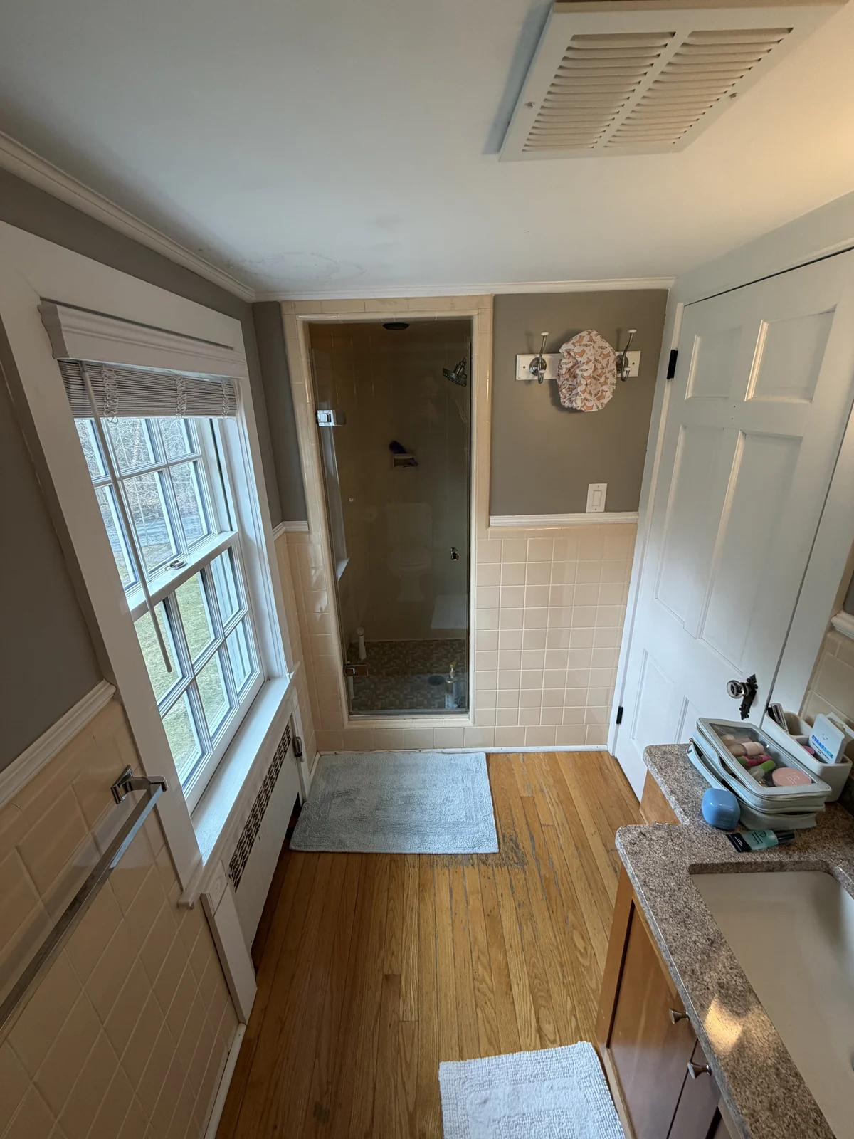 Bathroom before the remodel with an enclosed glass shower stall in the back alcove