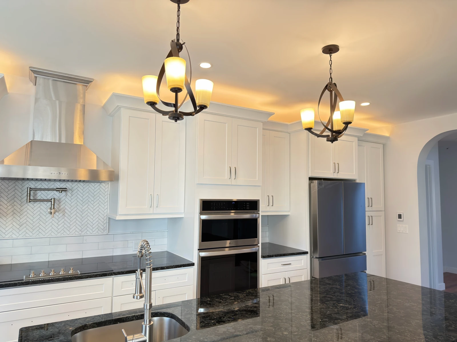 White kitchen with granite counters and wall ovens