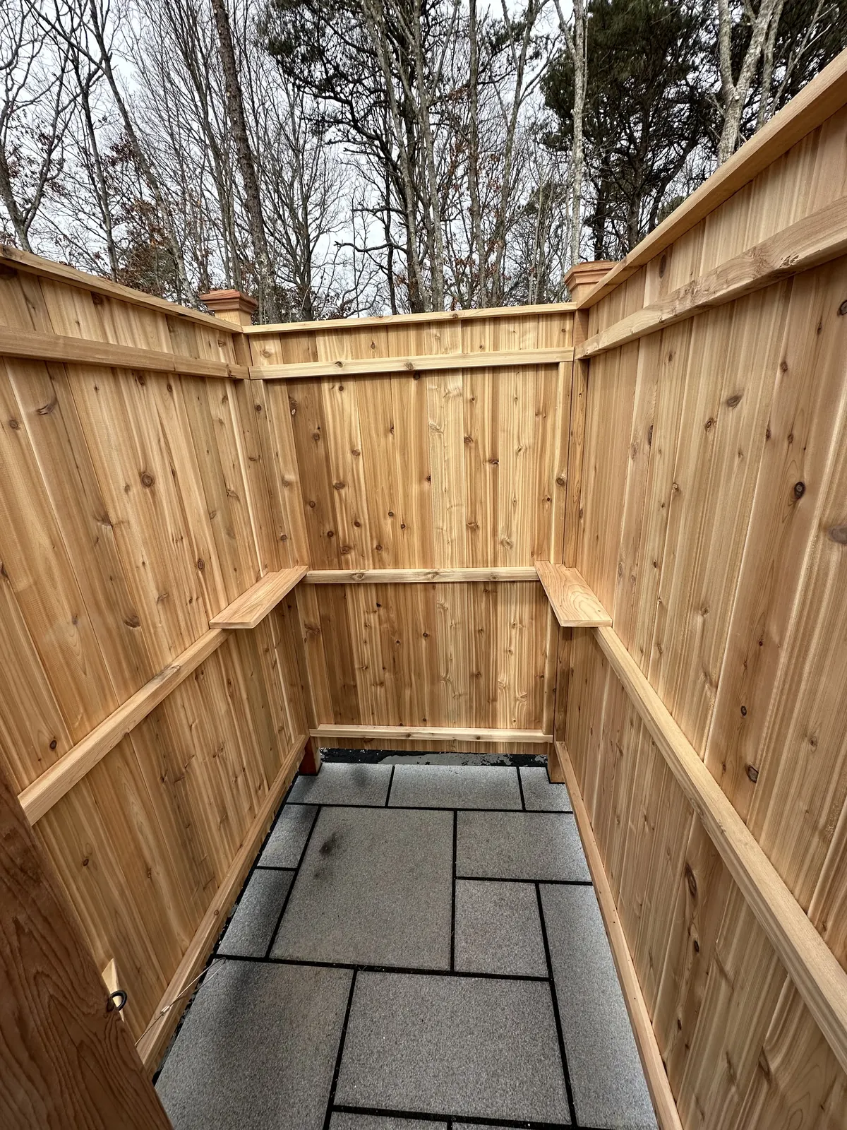 Inside a cedar outdoor shower with a paver floor